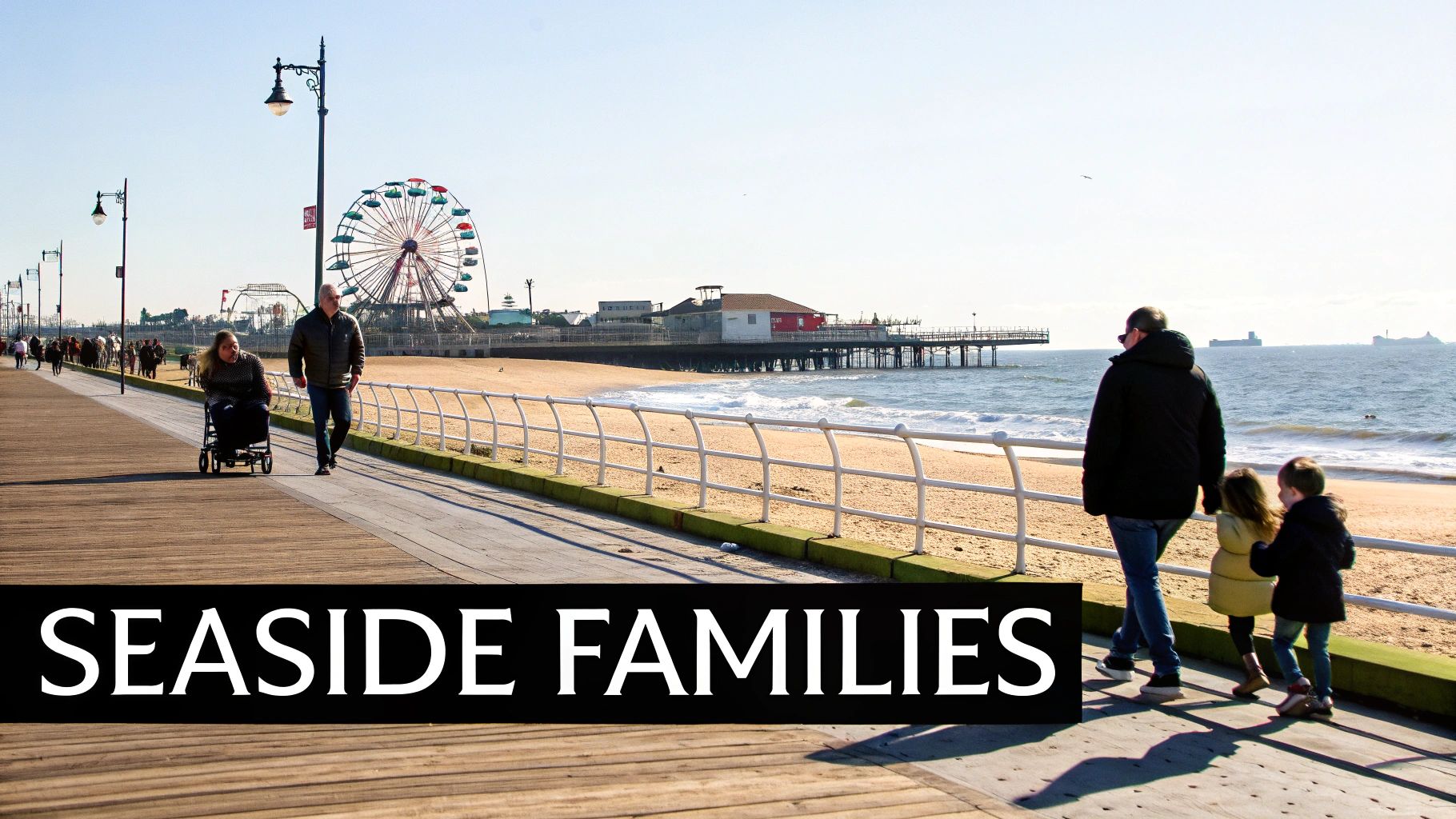 Families and people enjoy a sunny day on a bustling seaside boardwalk with a Ferris wheel.