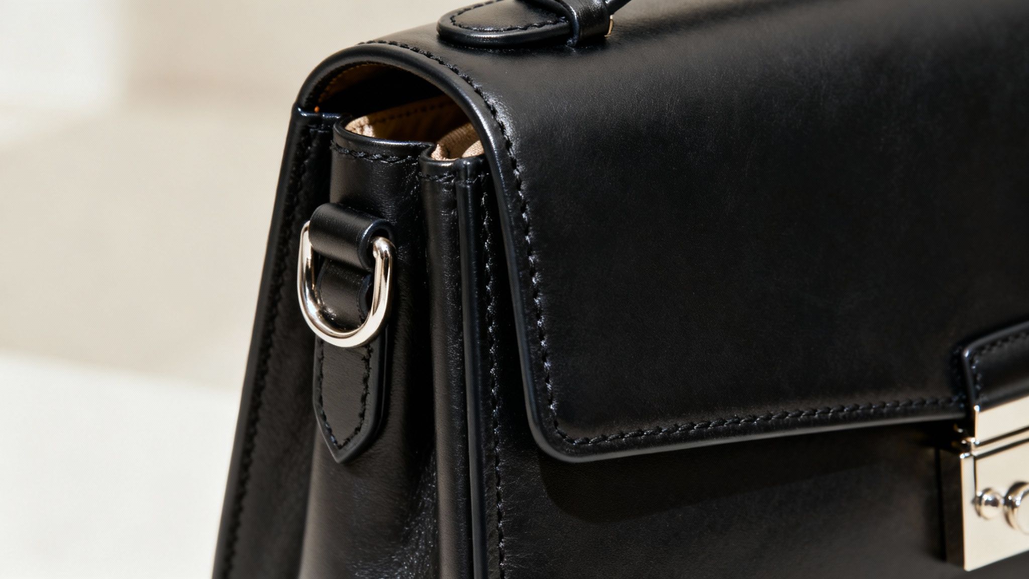 A close-up of the stitching and hardware on a designer black leather bag.